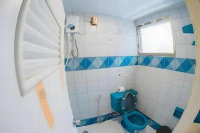 a bathroom with a blue toilet and a window at XX Mitr Inn Phuket Mueang Kao - มิตร อินน์ ภูเก็ต โอลทาวน์ in Phuket Town