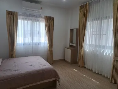 a bedroom with a bed and curtains and a television at Bancha white house in Ban Bo Han
