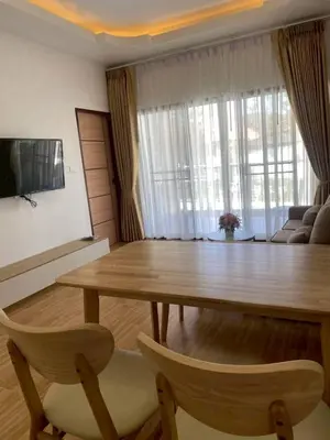 a living room with a wooden table and two chairs at Bancha white house in Ban Bo Han