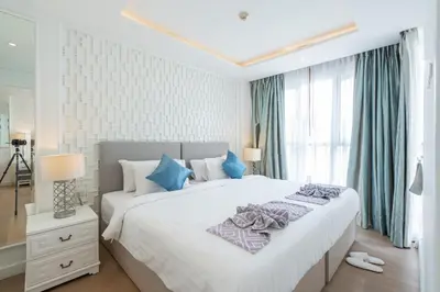 a white bedroom with a large bed with blue pillows at Seavale patong phuket in Patong Beach