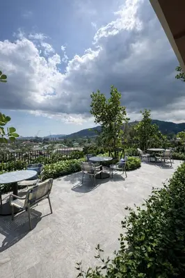 a patio with tables and benches and a view of a city at 2BR Apartment, 10-Min Walk to the Beach in Laguna Phuket