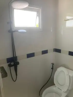 a bathroom with a toilet and a window at Nai Yang Guest House in Nai Yang Beach