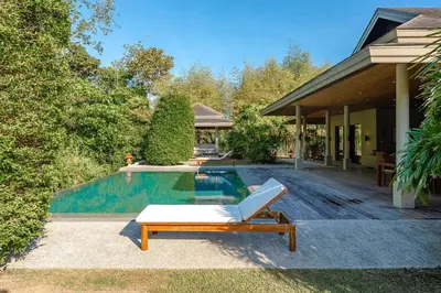 a pool with a lounge chair next to a house at Peaceful Retreat at Villa Langkah Luan, Mai Khao in Mai Khao Beach