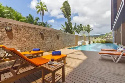 a patio with orange chairs and a swimming pool at CHIC CONDO - Cozy studio with mountain and sea views in Karon Beach
