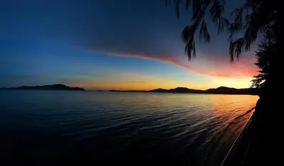 a sunset over the water with mountains in the background at Jasmine Seaview 'C' Friendly Guest House in Ban Saiyuan (1)