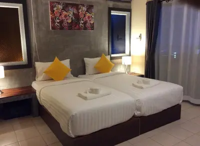 a bedroom with a large white bed with yellow pillows at The Meeting House Aonang - self service in Ao Nang Beach