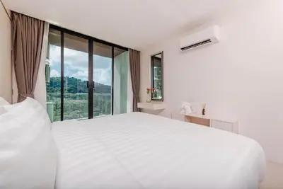 a white bed in a room with a large window at The Viva Patong Condo in Patong Beach