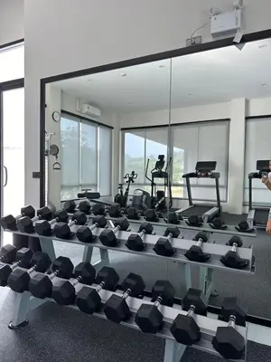 a gym with a large mirror and rows of exercise equipment at Title Halo Lemon Sky Naiyang Gym Pool Hammam in Ban Bo Han