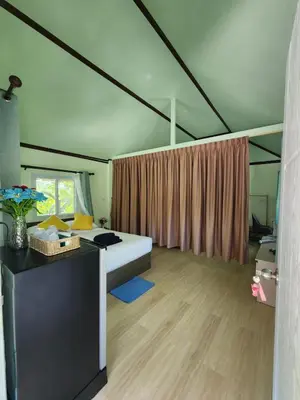 a bedroom with a bed and a desk and a window at Raya villa in Ban Muang Mai