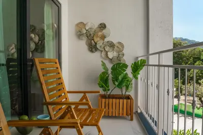 a rocking chair and a plant on a balcony at Title Halo Pinky Lime Naiyang Pool Gym Hammam in Ban Bo Han