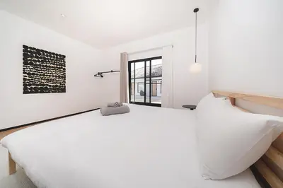 a white bedroom with a large bed and a window at wolin patong greeen resort in Patong Beach