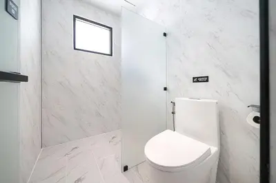 a white bathroom with a toilet and a window at wolin patong greeen resort in Patong Beach
