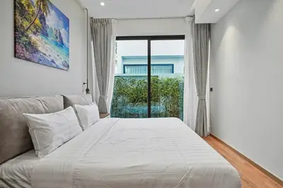 a white bed in a room with a large window at C32 Clover Residence Villa Phuket 3 bd in Ban Thalat Choeng Thale