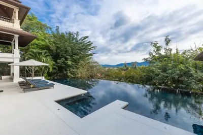 a swimming pool with two lounge chairs next to a house at 6-Bedroom Private Luxury Pool Villa in Layan in Thalang