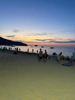 a group of people on the beach at sunset at 1 BDR 5 Swimming Pool Entire Apt Complex 5 Mins WALK To Naiyang Beach in Phuket