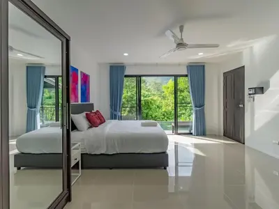 a bedroom with a bed with blue curtains and a mirror at Brand New Private pool villa Chalong Phuket Mountain view in Ban Klang