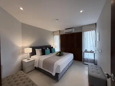 a bedroom with a large bed and a chair at Dewa 1302 Poolside Resort Spacious 2 Bedroom in Phuket Town