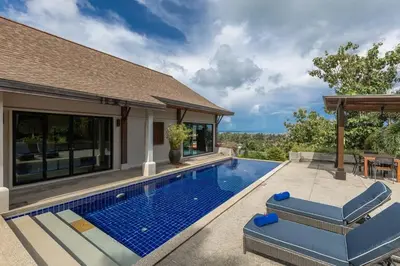 a swimming pool with blue chairs next to a house at Ao Yon- Contemporary 3-bedroom private pool villa in Ban Ao Makham