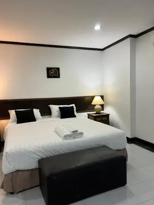 a bedroom with a large bed with a black ottoman at Pathaya in Ban Kata