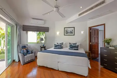 a bedroom with a large bed and a chair at Peaceful 2-Bedroom Villa on Loch Palm Golf Course in Ban Kathu