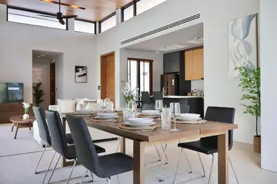 a dining room with a wooden table and chairs at Botanica - Bali Style Luxury 3 BR Private Pool Villa in Ban Pak Lak