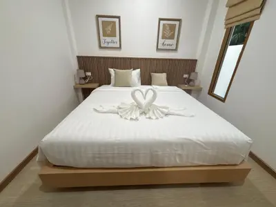a bedroom with a white bed with a flower on it at Falisa House Apartment Bangtao in Ban Thalat Choeng Thale