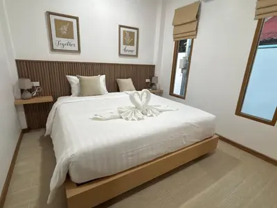 a bedroom with a white bed with a bow on it at Falisa House Apartment Bangtao in Ban Thalat Choeng Thale