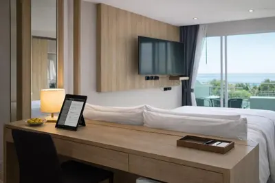 a hotel room with a bed and a desk with a television at Santosa Hotel & Welness Center in Ban Kata
