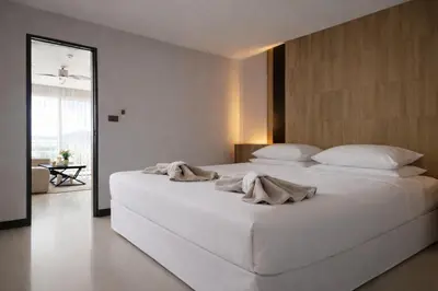 a bedroom with a large white bed with towels on it at Santosa Hotel & Welness Center in Ban Kata