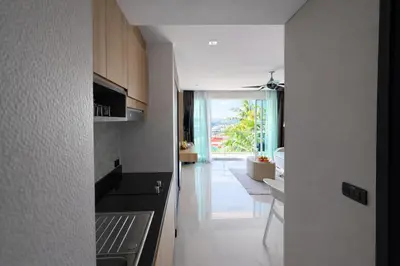 a kitchen with a door leading to a living room at Santosa Hotel & Welness Center in Ban Kata