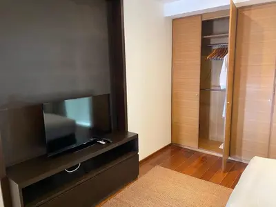a living room with a flat screen tv and a closet at Beachfront 2 BR Luxury Condominium Surin in Surin Beach