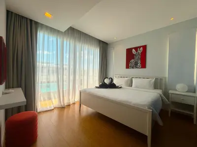 a bedroom with a bed and a large window at The Pelican Residence & Suites Krabi in Ban Ko Kwang