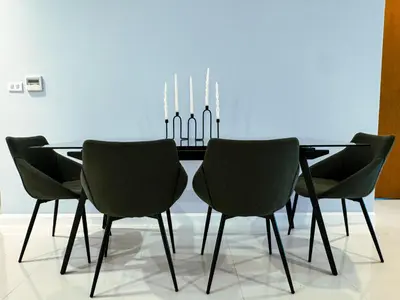 a dining room table with four chairs in front of a blue wall at The Pelican Residence & Suites Krabi in Ban Ko Kwang