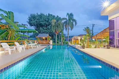 a pool at a resort with chairs and trees at Tom Star Pool Villa Layan in Thalang