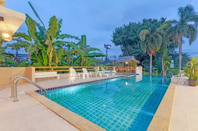 a swimming pool in a resort with chairs and trees at Tom Star Pool Villa Layan in Thalang