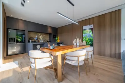 a kitchen and dining room with a wooden table and white chairs at Cocoon Villa 6 - Eden Escape 3 BR - Pool - Garden in Ban Sakhu
