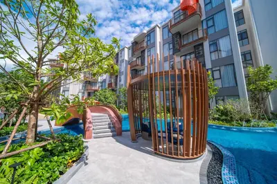 an apartment complex with a playground in front of a pool at Canvas Cherngtalay Holiday Apartments in Laguna Phuket