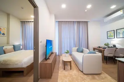 a bedroom with a bed and a couch and a television at Canvas Cherngtalay Holiday Apartments in Laguna Phuket