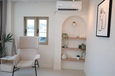 a white living room with a white chair and a window at Breeze House Patong in Patong Beach