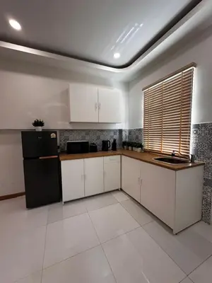 a kitchen with white cabinets and a black refrigerator at Patong Relax Home in Patong Beach