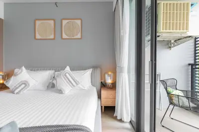 a bedroom with a white bed and a chair at Serenity 2bd apartments in Cassia in Laguna Phuket