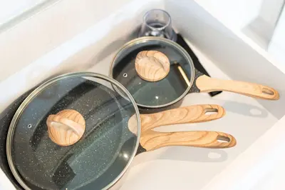 two frying pans and wooden utensils on a stove at Serenity 2bd apartments in Cassia in Laguna Phuket