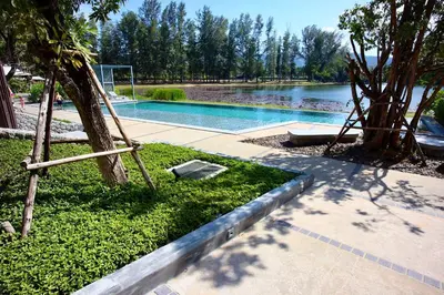 a swimming pool with a tree and a swing at Serenity 2bd apartments in Cassia in Laguna Phuket