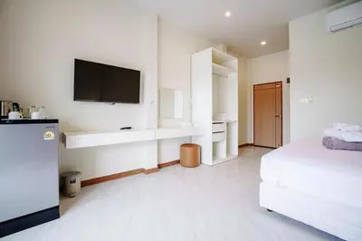 a white room with a bed and a flat screen tv at 1 bedroom apartment - 2 min to the Nai Harn beach in Rawai Beach