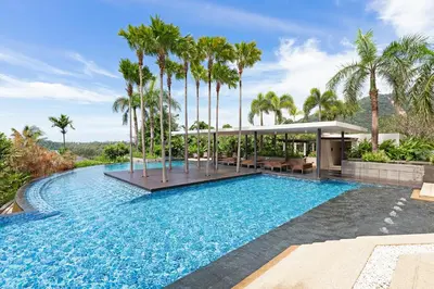 a swimming pool with palm trees in front of a house at The Heights C3 SeaView 2 BR, 5min to Kata Beach in Ban Karon