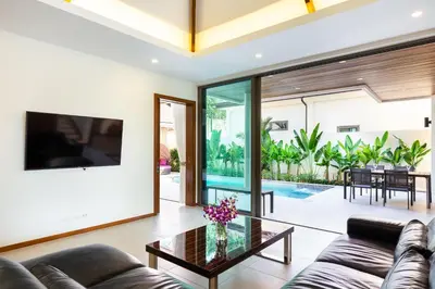 a living room with a couch and a glass table at Tropical 4 BR Pool Villa Mika in Rawai Beach