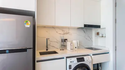a kitchen with white cabinets and a washer and dryer at Studio 50 meter from Layan Beach in Layan Beach