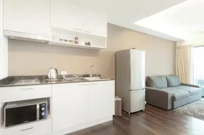 a kitchen with a refrigerator and a couch in a room at Beach Front Condo on Rawai Beach in Rawai Beach