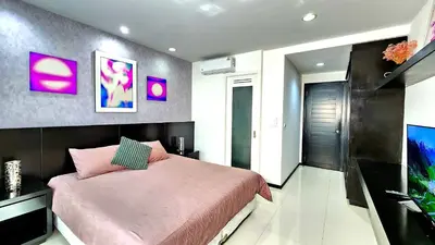 a bedroom with a pink bed and a flat screen tv at Phuket KAMALA Apartment in Phuket Town