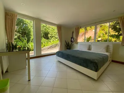 a bedroom with a large bed and large windows at Andaman Hills pool Seaview house in Patong Beach